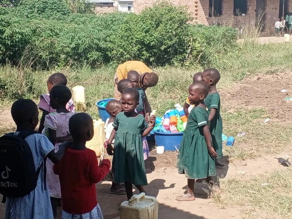 Children gathered around shared containers during a community water activity