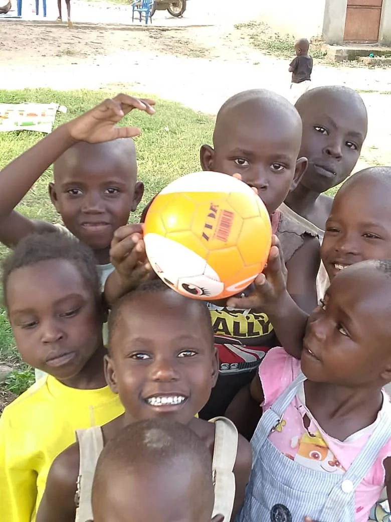 Children smiling together around a football outdoors.