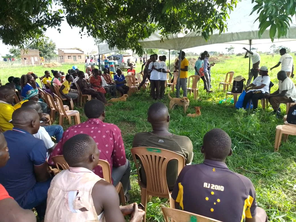 Community members seated outdoors during a local outreach meeting