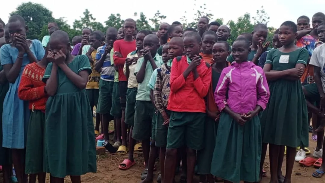 School children gathered together outdoors during a community activity.