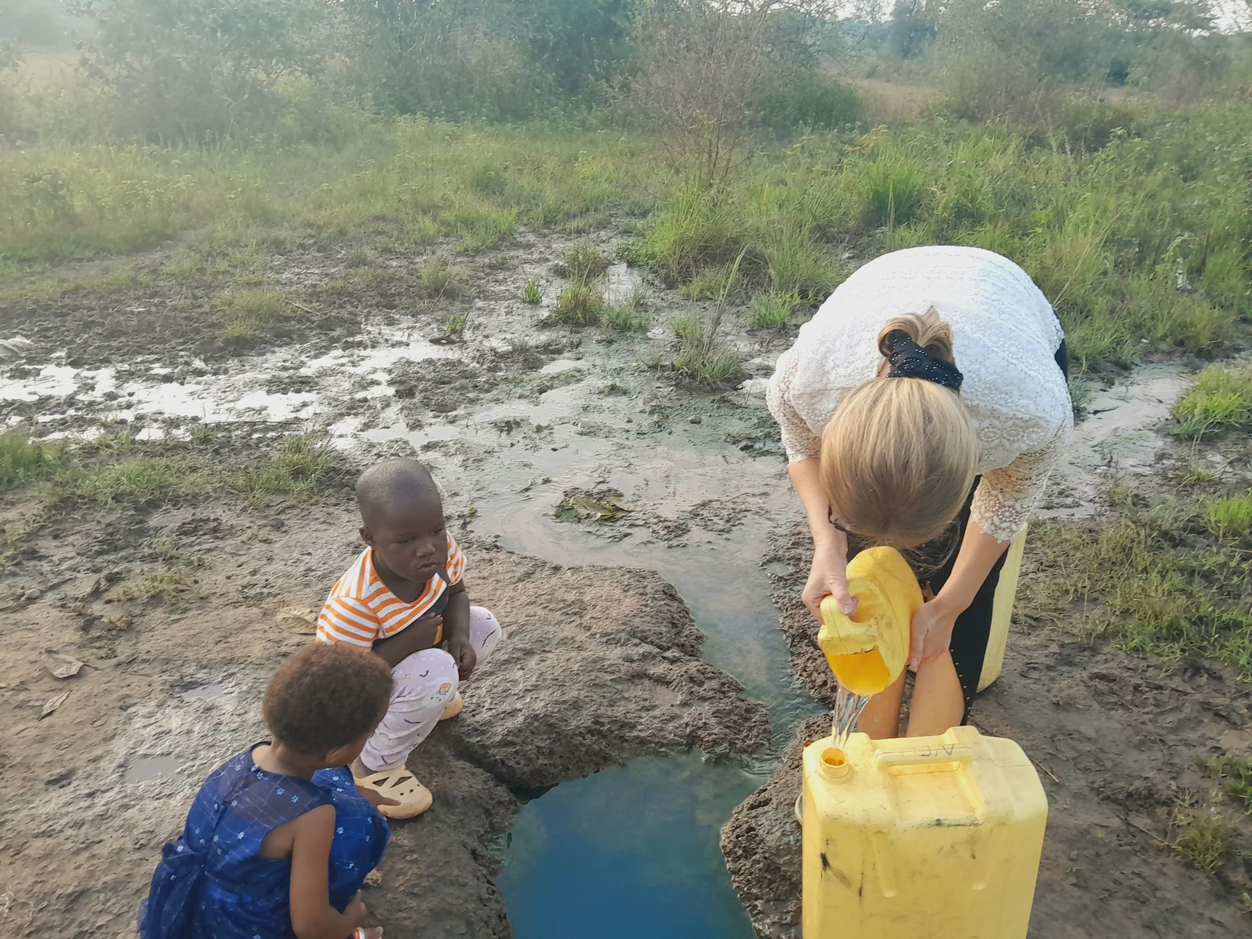Hand pump and yellow water containers at a school water point
