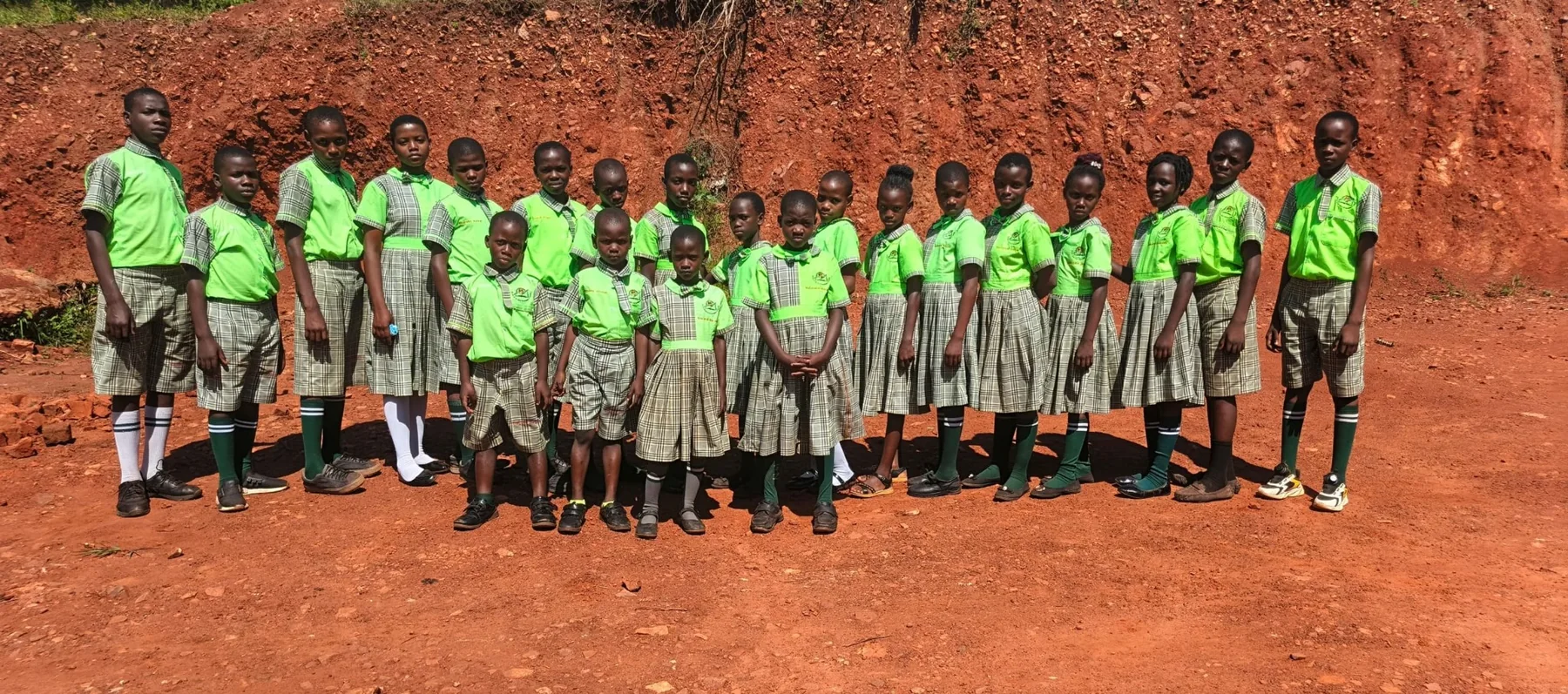 Pupils standing together in green school uniforms