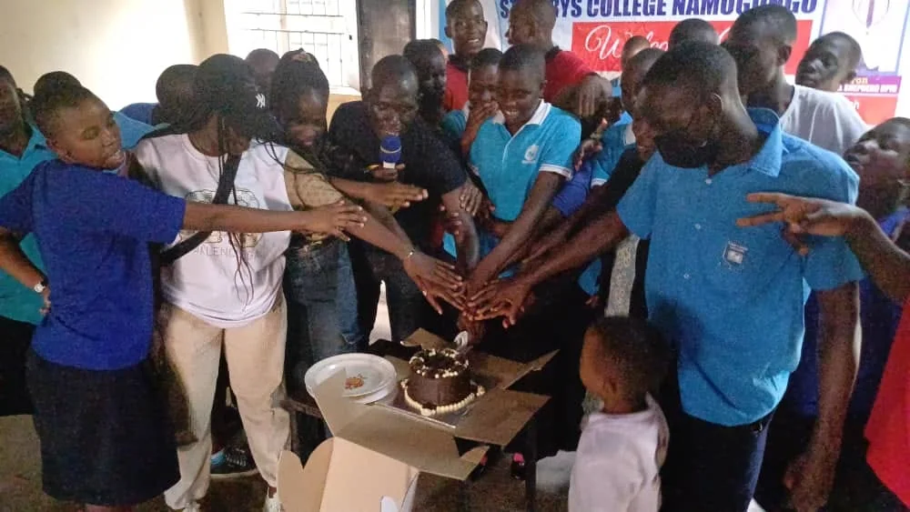 Young people gathered around a cake during a community celebration.